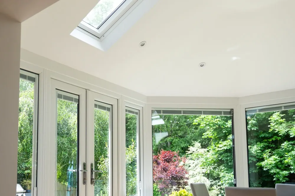 Inside a conservatory with a plastered warm roof ceiling and Velux window